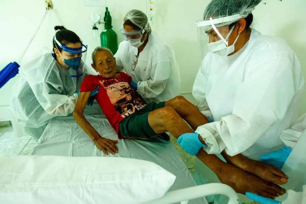 The MSF team helps 99-year-old patient Antonio Castro at the MSF care center in São Gabriel da Cachoeira. He was under observation for a few days with breathing difficulties. ©Diego Baravelli/MSF