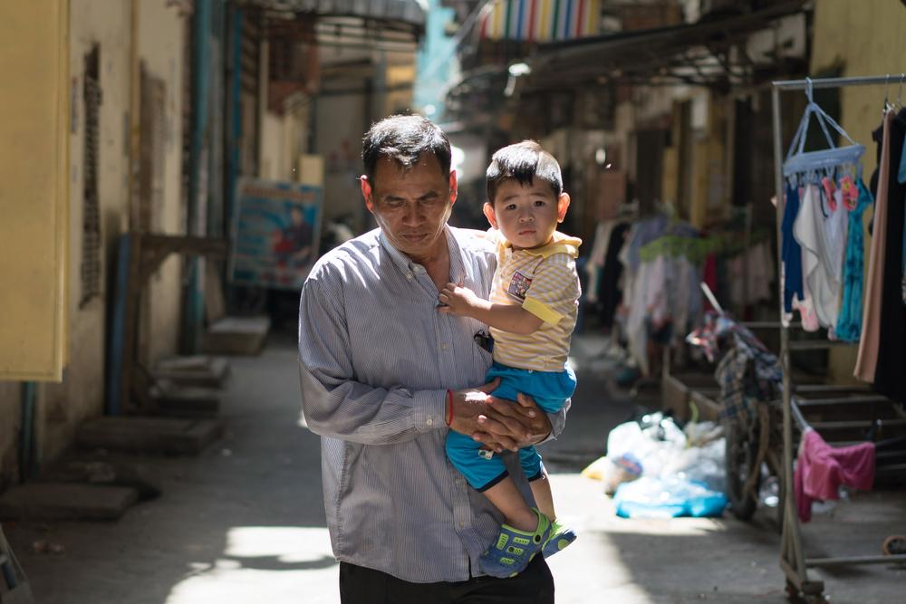 Din Savorn, 50, carries his son to daycare in Phnom Penh, Cambodia. April 2017. © Todd Brown