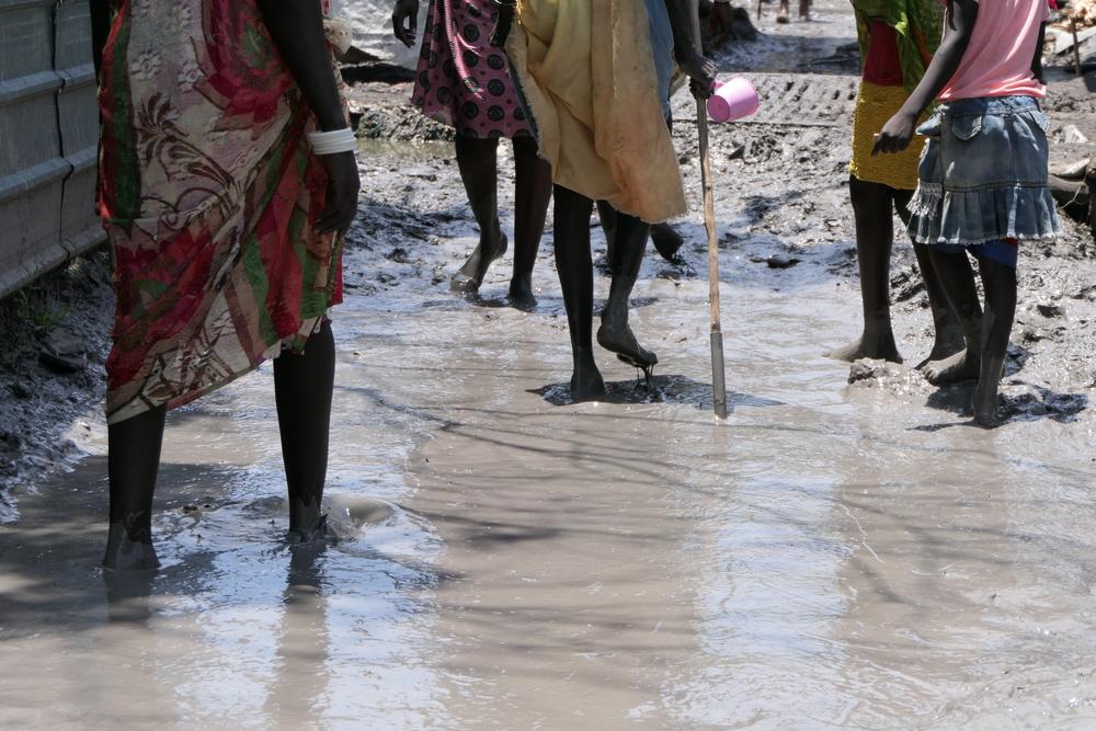 People walk in the muddy water in the middle of Old Fangak market. South Sudan, 2021. © Damaris Giuliana/MSF