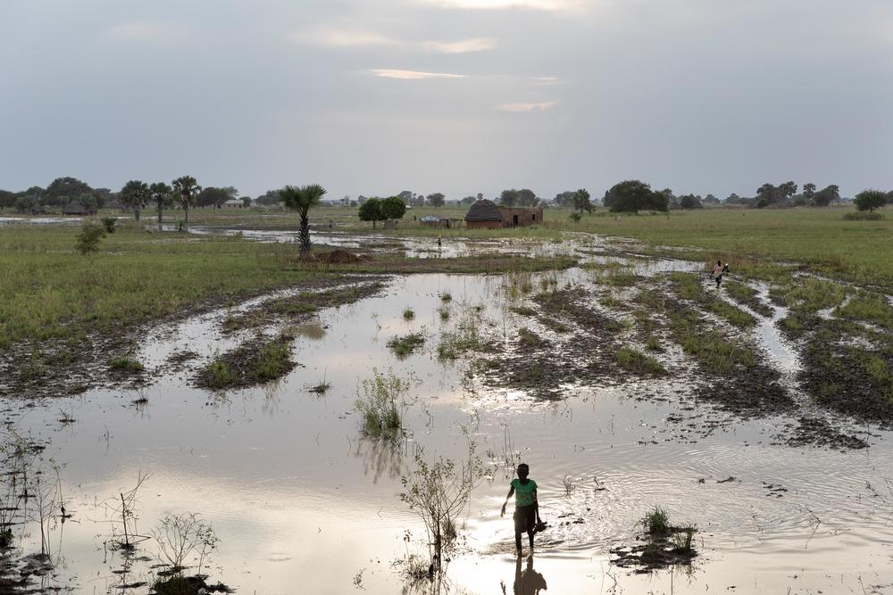 A girl walks through a flooded area on her way home near Aweil Town. South Sudan, 2021. © Adrienne Surprenant/Item