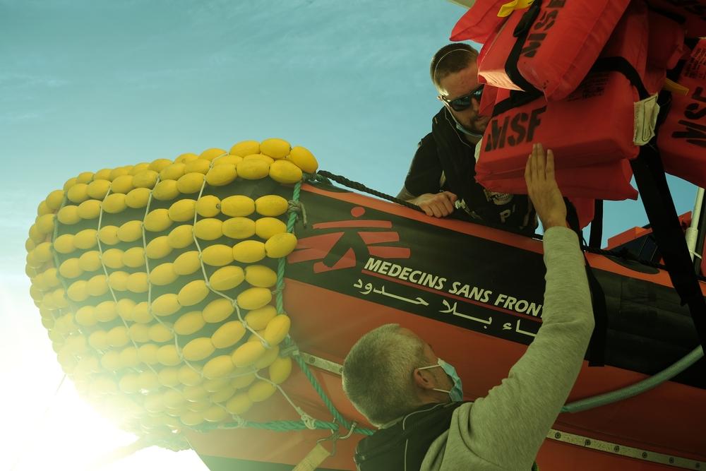 After securing the rescue RHIB on board the Geo Barents, an MSF crew member passes lifejackets to a deck hand. Augusta, Sicily. February © Kenny Karpov