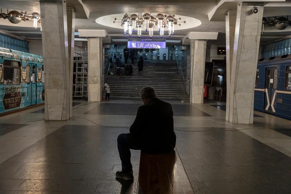 A man sits on a metro bench, between wagons where people now live, hiding fromthe shelling. Kharkiv, Ukraine, April 11, 2022. © Adrienne Surprenant/MYOP