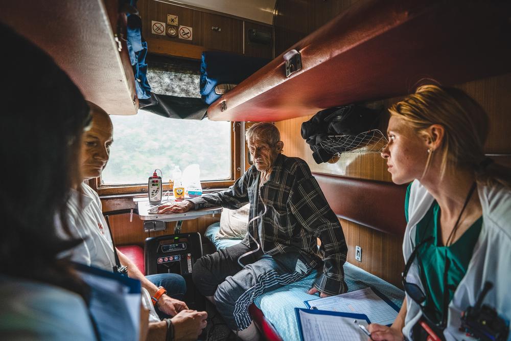 The medical team on board the MSF medical train discuss the condition of an eldelry war-wounded patient 