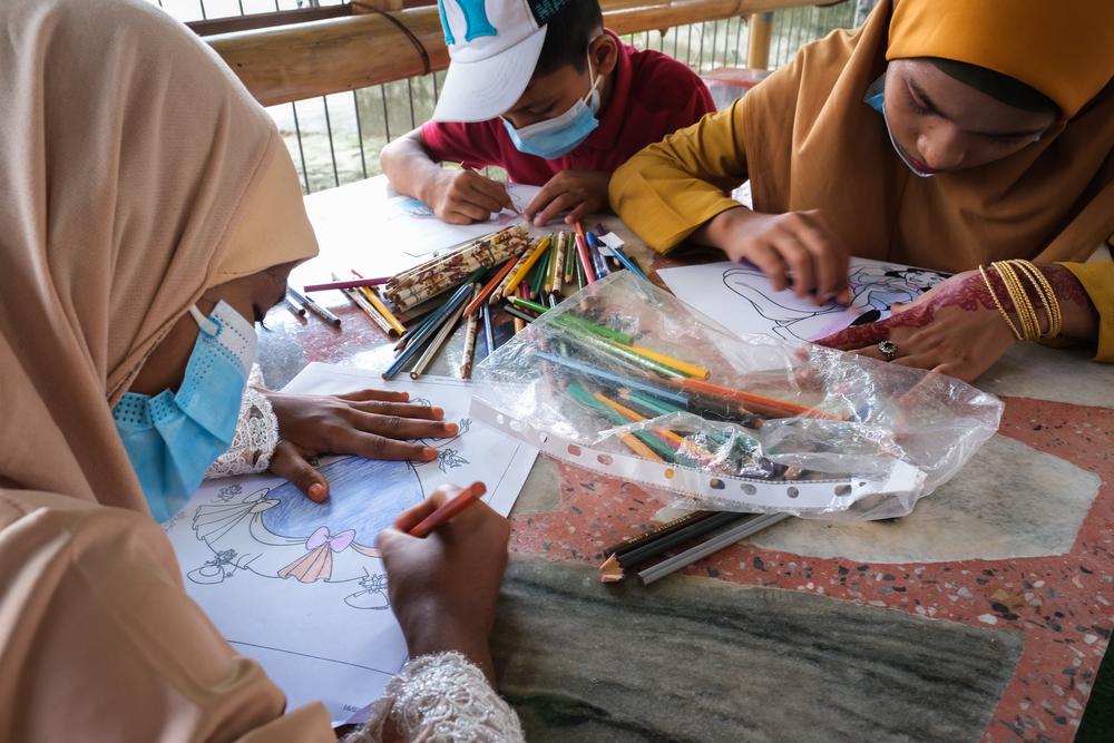 Newly arrived Rohingya children colouring while waiting.