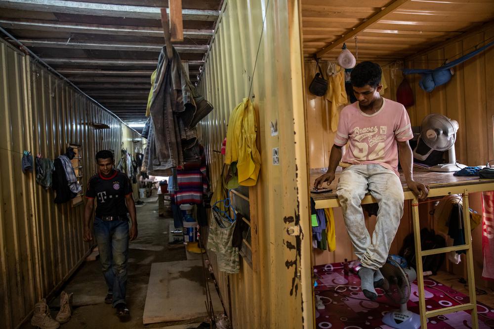 Nur, 27 years old (right), shares this container with seven other Rohingya workers.
