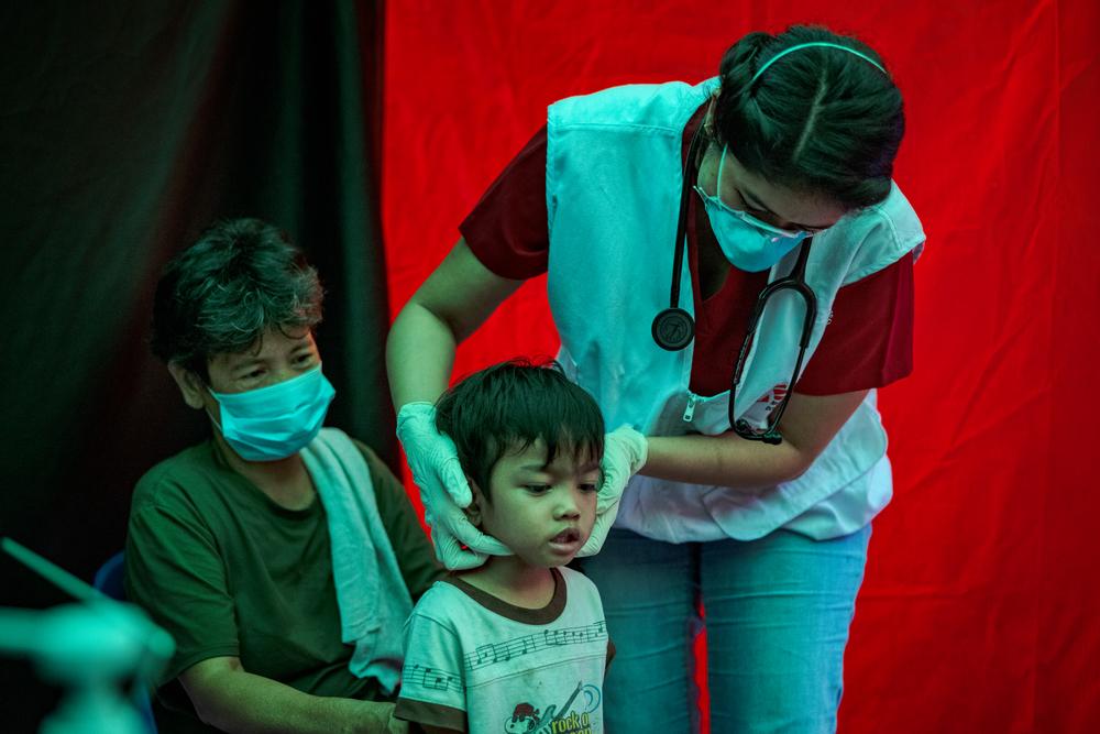 A grandmother watches as Doctors Without Borders TB doctor, conducts a medical evaluation of her grandson. Philippines, 2023. © Ezra Acayan