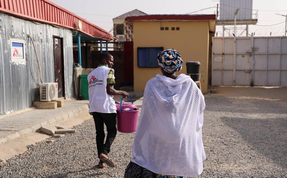 A Doctors Without Borders health promoter accompanies a mother with her child after being discharged from the under-six ward of the Nilefa Kiji nutrition centre. Nigeria, April 2023.