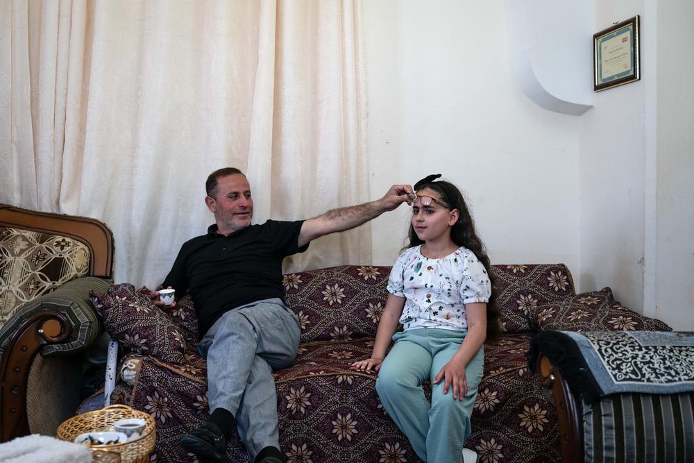 Yasser Abu Markhiyeh shows his daughters eye damaged during a settler attack when she was an infant, in his home in Hebron. Palestine, May 2023. © Samar Hazboun