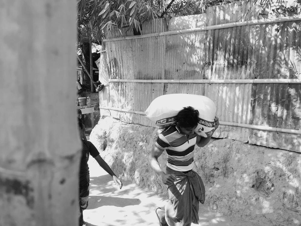 An image of a Rohingya man carrying food ration.
