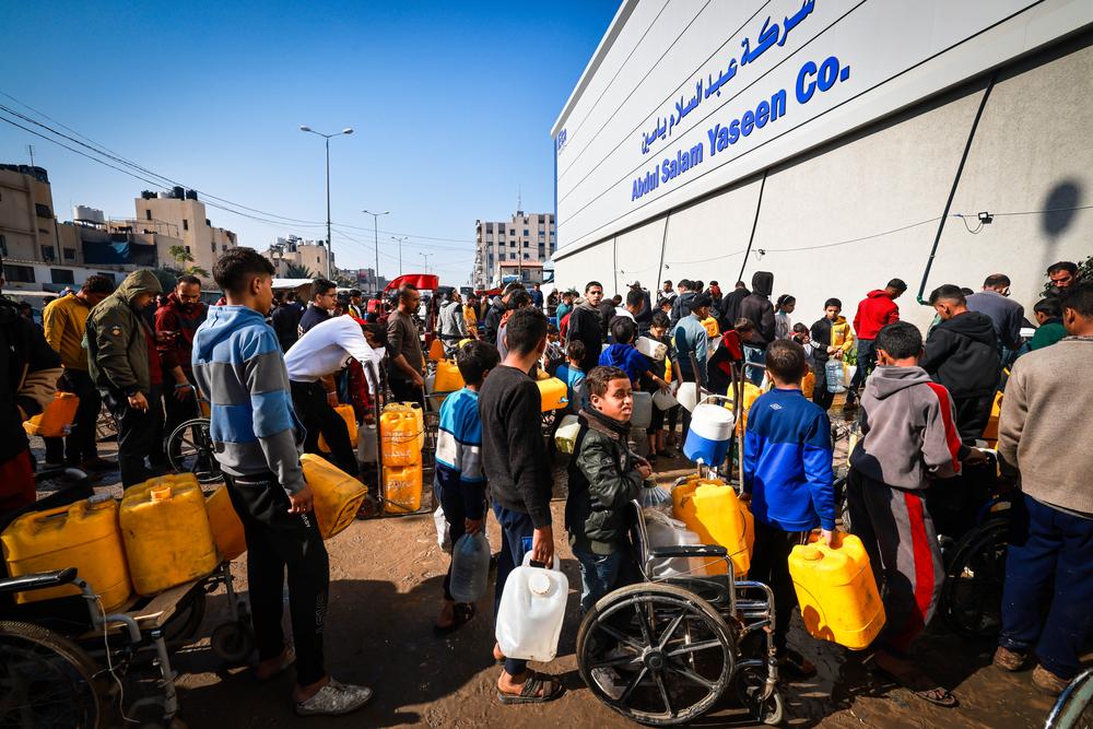 A group of displaced Palestinians waits in front of Abed Al-Salam Yassin company in the Tal Al-Sultan area of the southern Gaza town of Rafah. Palestinian Territories, February 2024. © Mohammed Abed