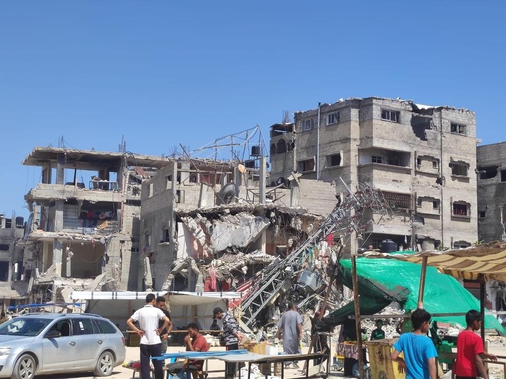 People stand in front of a bombed out building in Rafah