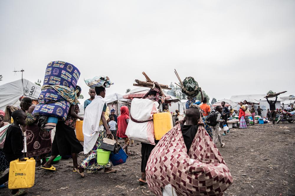 Families leave the Lushagala and Bulengo camps, carrying their packages on their backs and heads.