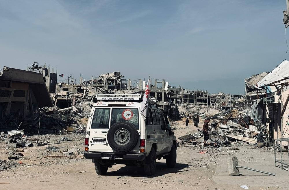 An MSF vehicle passes in front of ruined buildings in Jabalia.