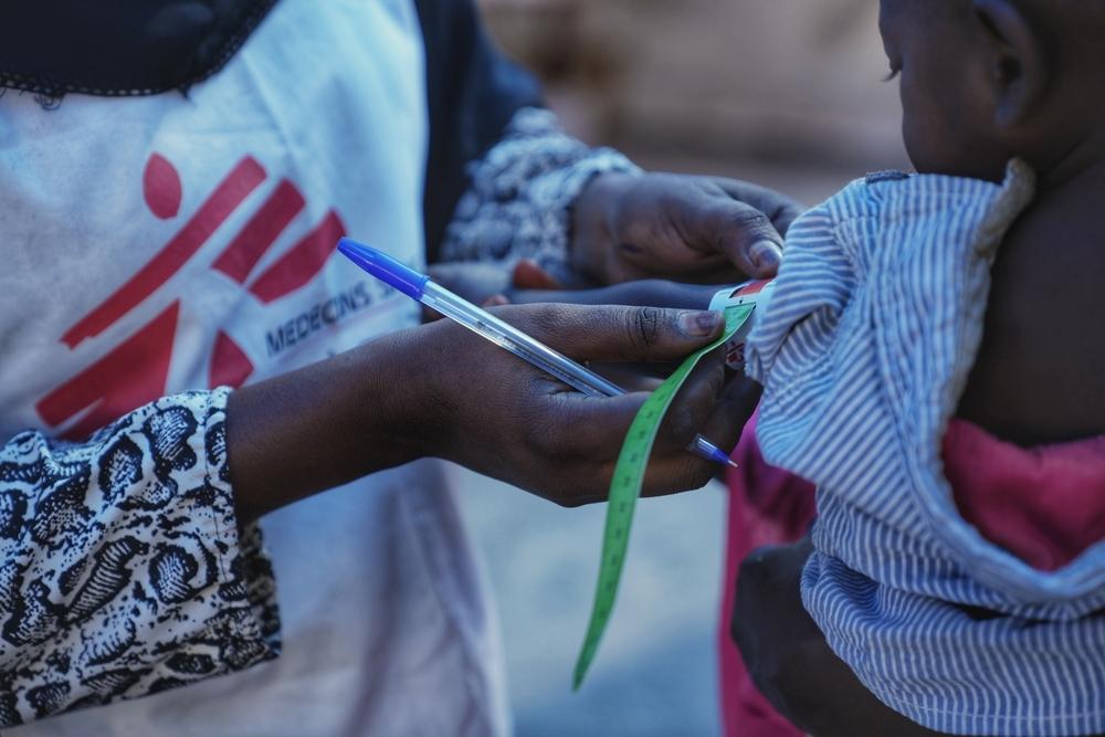 a staff measure a child with MUAC