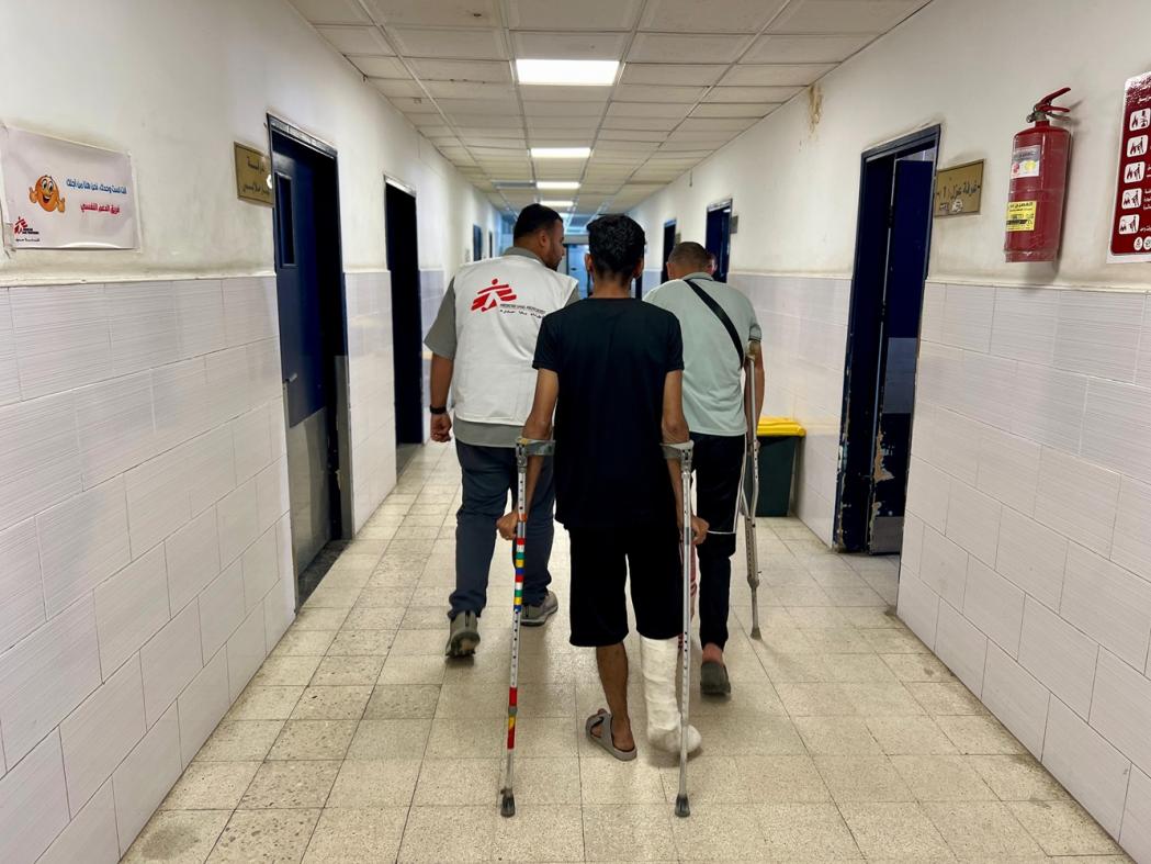 Two patients on crutches with MSF staff in a hospital