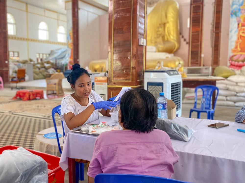 A staff giving gout medicine to a patient at the moble clinic set up inside a monastery
